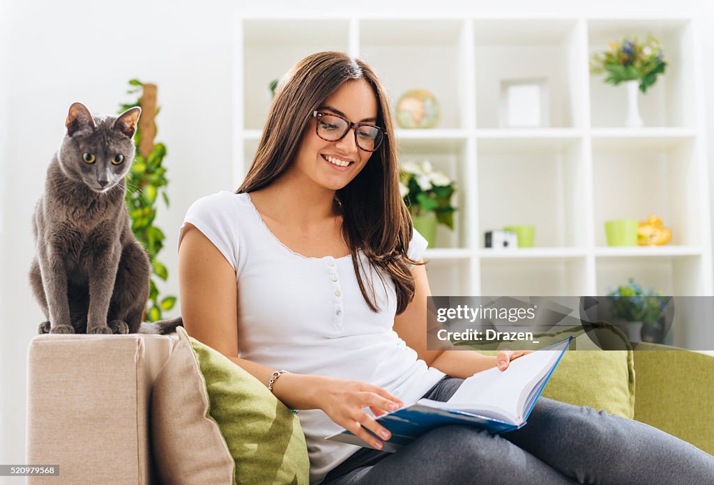 Woman sitting in living room with notebook and smiling