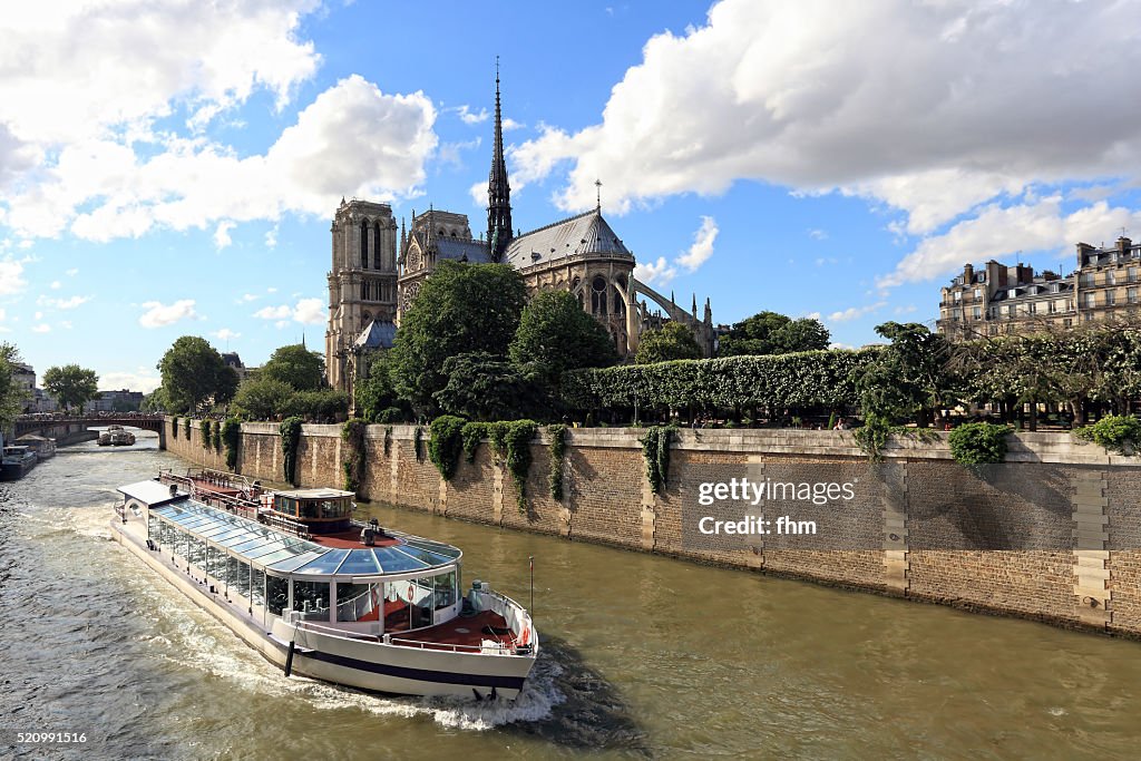 A sightseeing boat on Seine River in Paris is passing Notre Dame