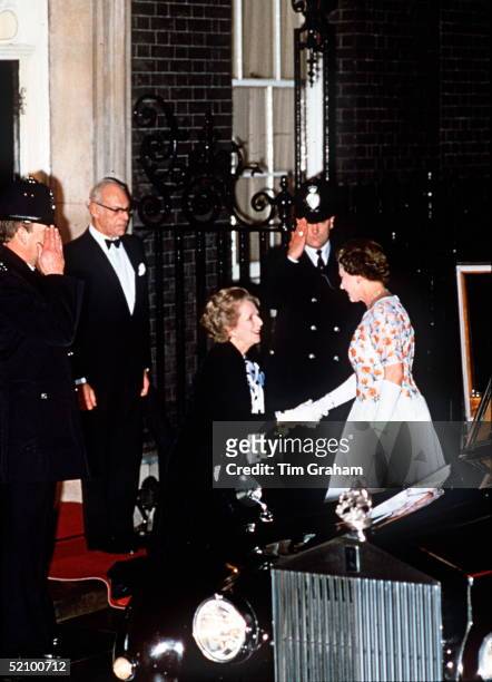 The Prime Minister Margaret Thatcher Curseying To The Queen At 10 Downing Street. Her Husband Dennis Thatcher Is Standing Behind.
