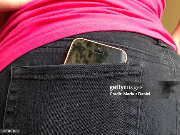 Pink iPhone in girl's black jeans back pocket