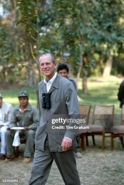 Prince Philip Smiling As He Walks Through Chitwan Park. He Has A Pair Of Binoculars Around His Neck.