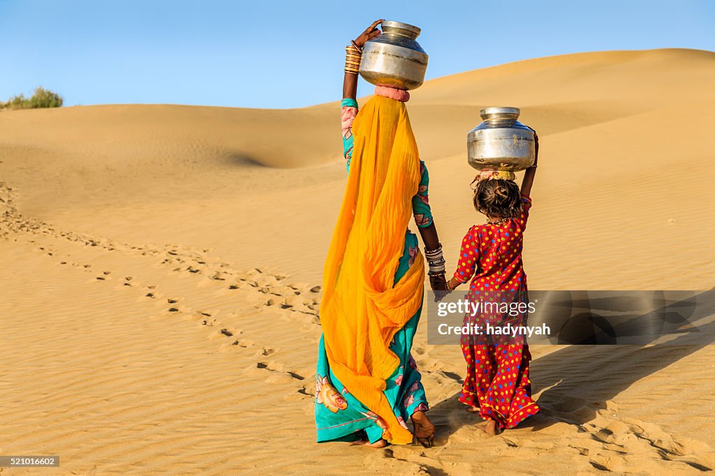 Indische Frau mit kleinen Tochter, die Wasser von gut