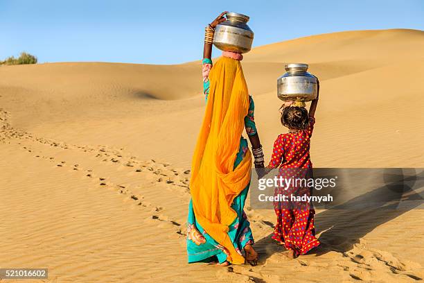 donna indiana con piccola figlia portando l'acqua e - rajasthan foto e immagini stock