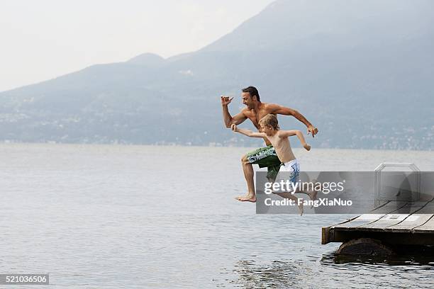 padre e hijo saltando del muelle - eventos de la vida fotografías e imágenes de stock