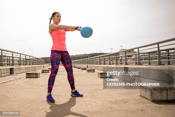 sportswoman exercising with kettlebell on the bridge - kettle bells stockfoto's en -beelden