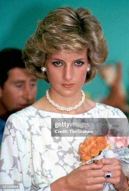 Diana, Princess Of Wales Looking Sad During An Official Overseas Visit. She Is Wearing Pearl Necklace And Earrings And Holding A Bouquet Of Roses.