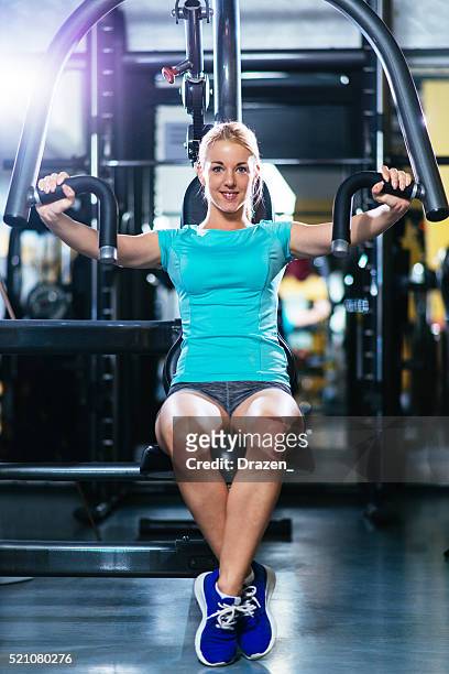 blonde athlete pushing weights for pectoral muscles and torso - pectoral muscle stock pictures, royalty-free photos & images