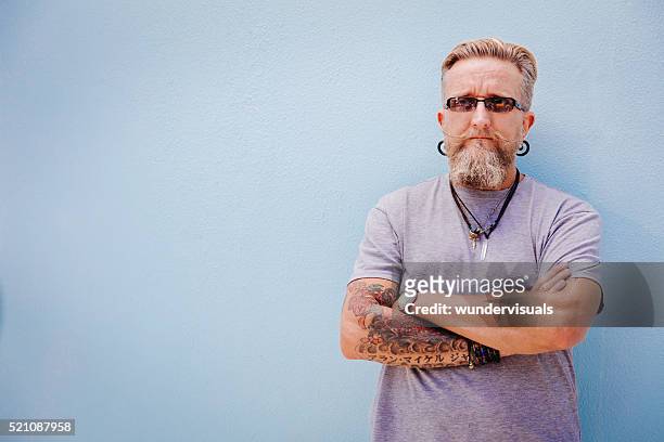 eccentric mature man with tattoo and earrings - earring stud stock pictures, royalty-free photos & images