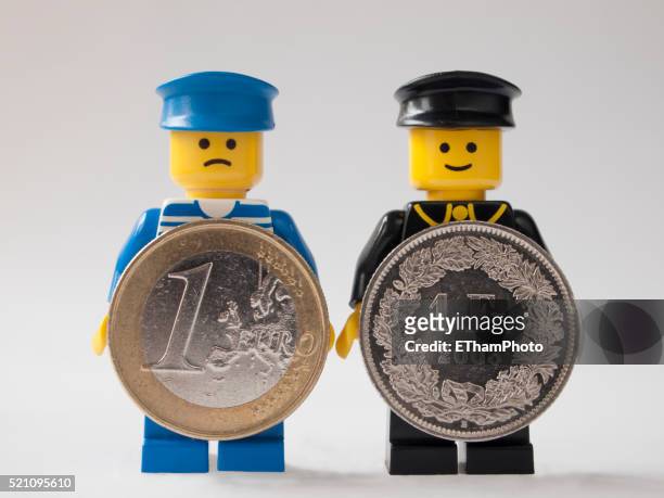 lego men holding euro and swiss franc coins - schweiz eu stock-fotos und bilder