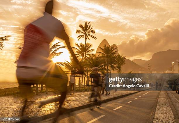 bicycle rider at sunset on ipanema beach, ipanema, rio de janeiro, brazil - río de janeiro fotografías e imágenes de stock