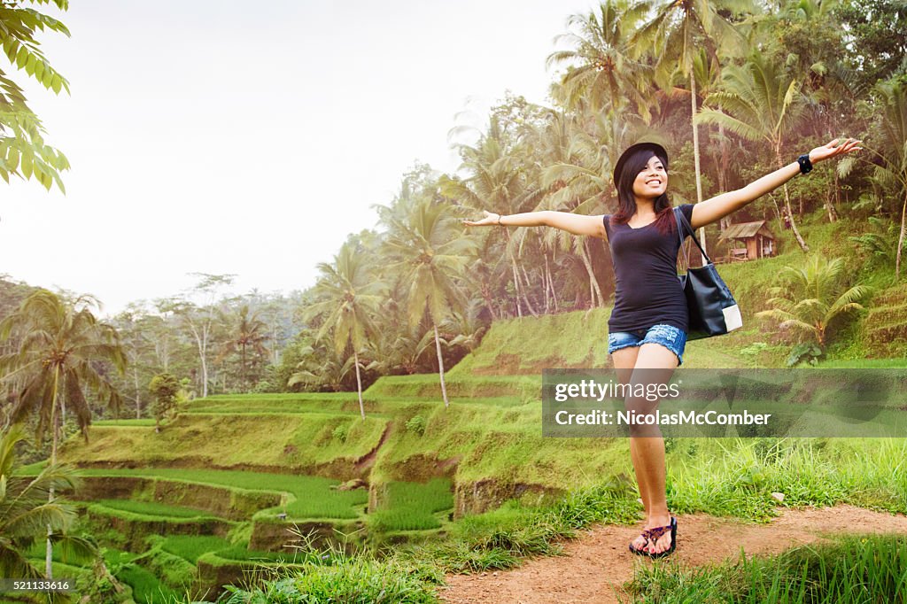 Happy young Indonesian woman proudly shows off Bali landscape