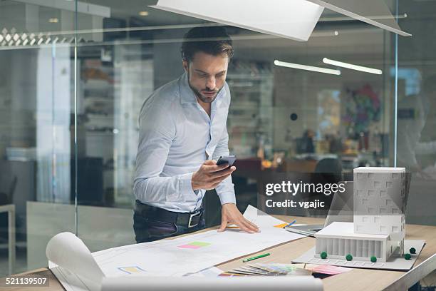designer typing on smart phone in office. - man examining stock pictures, royalty-free photos & images