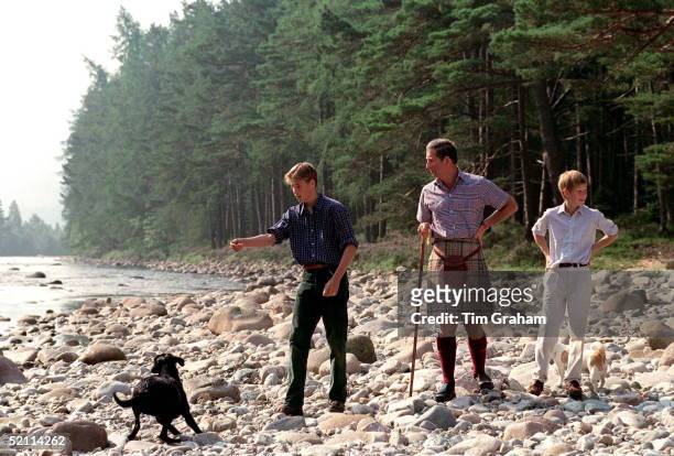 Prince Charles With Prince William & Prince Harry At Polvier, By The River Dee, Balmoral Castle Estate. Prince William Throwing Stones For His Black...