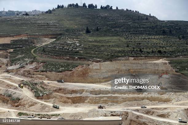 Workers and buldozers work at a construction site on April 14, 2016 in the Israeli settlement of Givat Zeev near the West Bank city of Ramallah....
