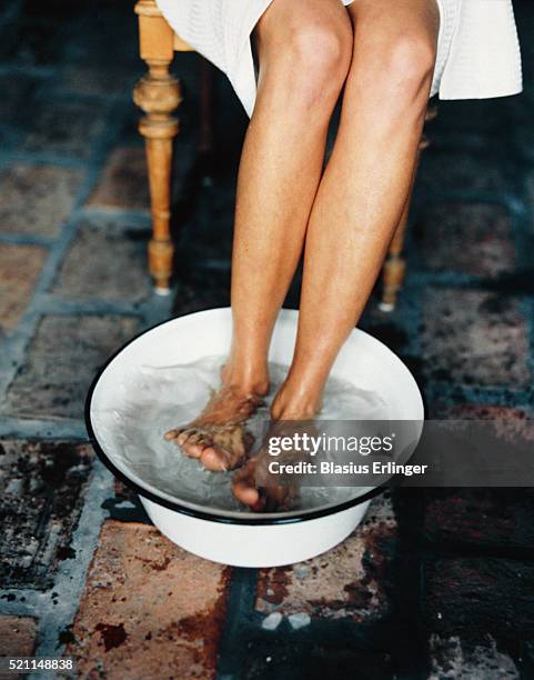 woman soaking feet in basin - bassine photos et images de collection