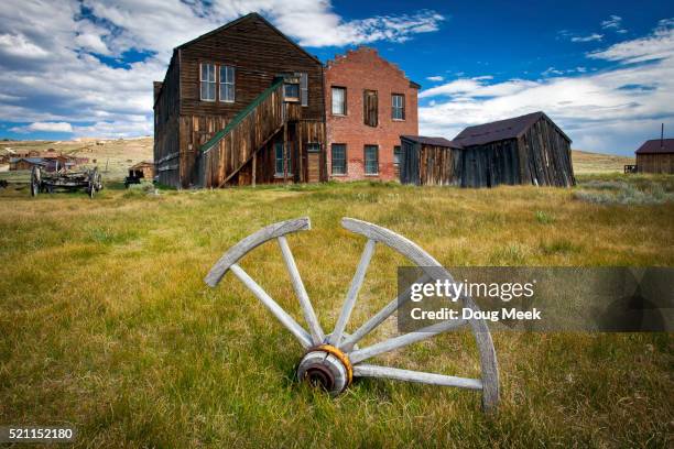 wagon wheel buried in grass - ghost town stock pictures, royalty-free photos & images