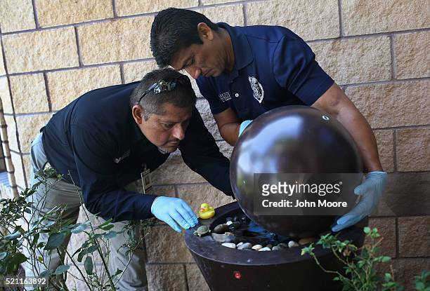 City environmental health specialists Aaron Salazar , and Gerardo Valdez check standing water for mosquito larvae outside a home on April 14, 2016 in...
