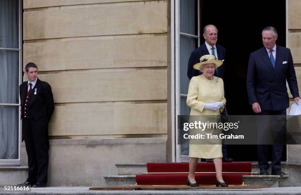 Footman Wearing His Medal To Mark The Golden Jubilee Watches As Queen Elizabeth II Walks Out Of Buckingham Palace Into Her Garden For A Children's...