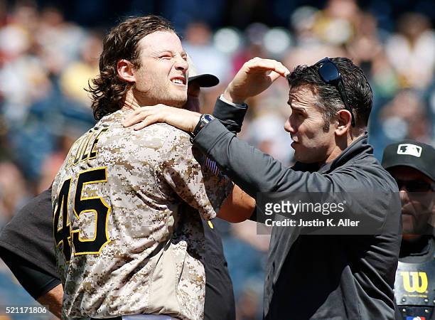 Gerrit Cole of the Pittsburgh Pirates is tended to by athletic trainer Ben Potenziano after being struck in the head by a hit up the middle in the...