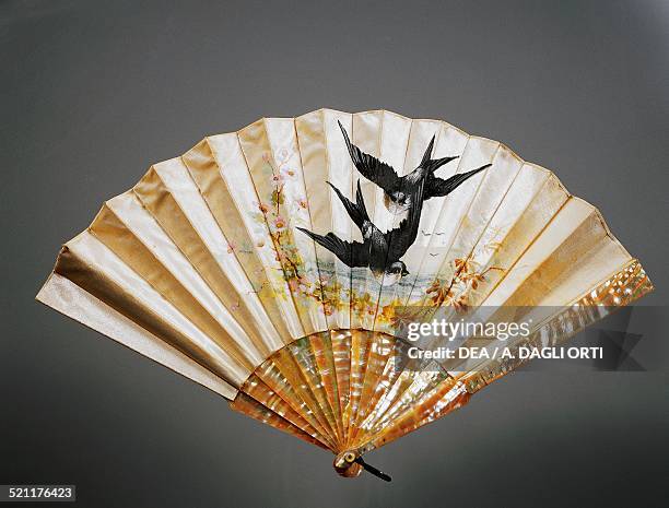 Hand fan with swallows amongst the branches of peach blossoms, tempera-painted satin with iridescent mother of pearl ribs, ca 1900. Italy, 19th...