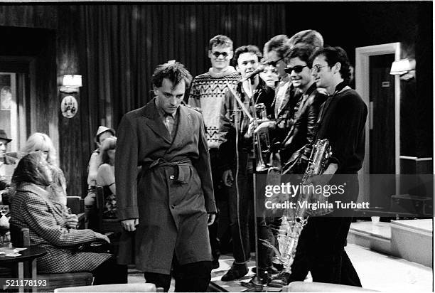 Rik Mayall as Rick stands in front of the members of the band Madness, on set during the filming of The Young Ones episode 'Boring', UK, 19 August...