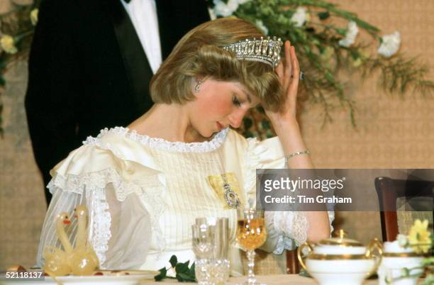 Princess Diana Adjusting Her Tiara During Banquet In New Zealand. Her Cream Silk Organza Frilly Evening Dress Was Designed By Fashion Designer Gina...