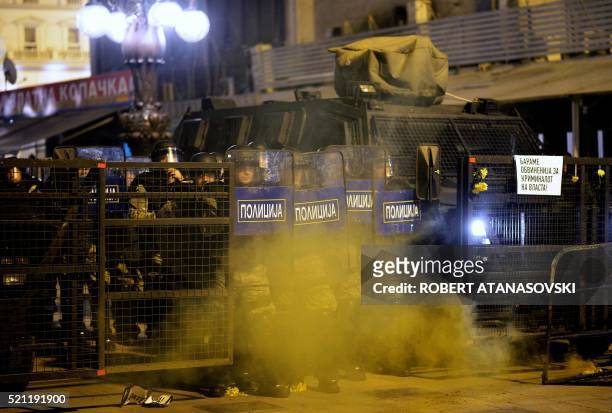 Anti-riot police officers stand guard in front of protestors in Skopje on April 14 during a protest against the president's shock decision to halt...