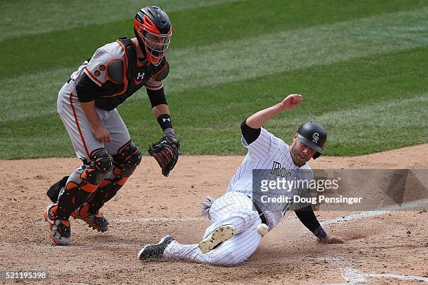 Mark Reynolds of the Colorado Rockies slides home to score as he is hit by the ball on the throw from Angel Pagan of the San Francisco Giants on a...