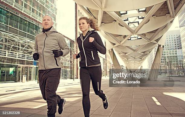blonde athletic woman and shaved coach jogging together in city - running netherlands stock pictures, royalty-free photos & images