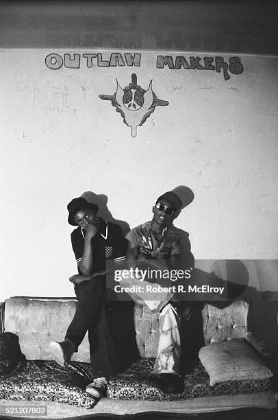 Portrait of two unidentified members of Bronx street gang the Outlaw Makers as they sit on a couch in their clubhouse, New York, New York, 1975.