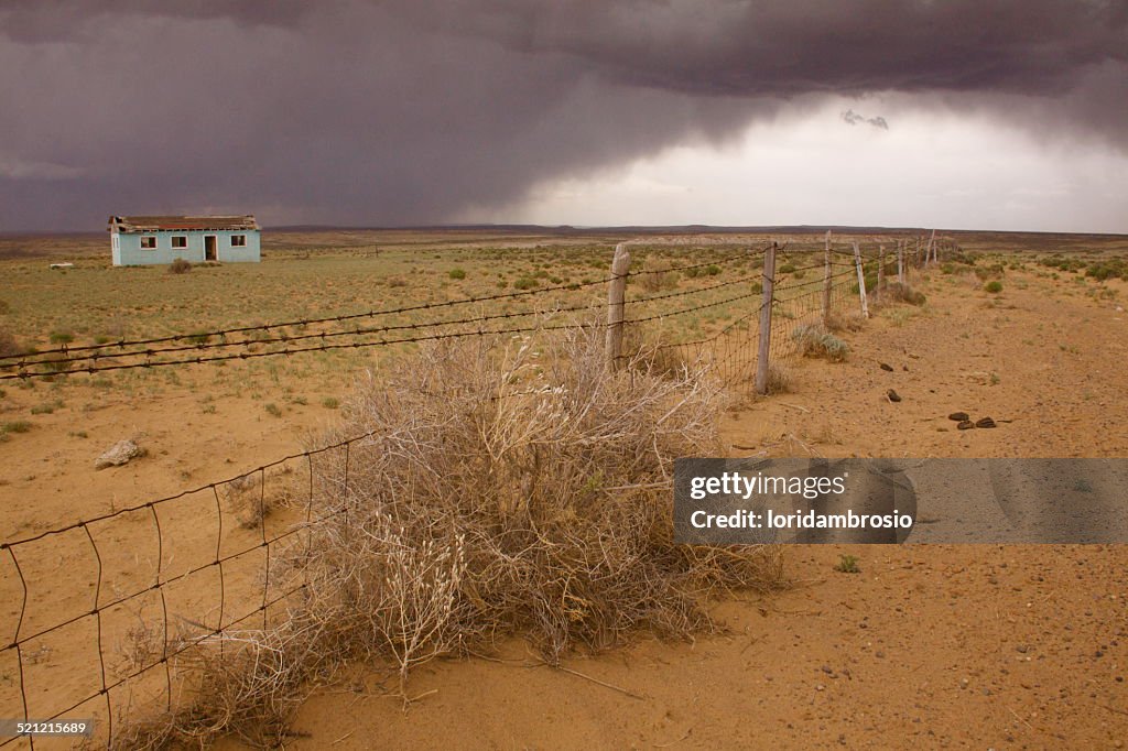 Stormy skies/lone house desert landscape