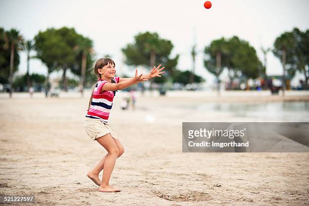 little girl playing throw and catch on the beach - gooien stockfoto's en -beelden
