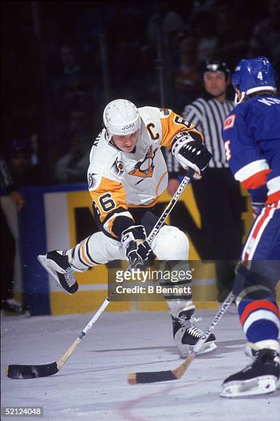 Canadian professional hockey player Mario Lemieux , captain of the Pittsburgh Penguins, looks to make a shot on the New York Islanders goal as German...