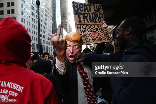 Man in a Donald Trump mask joins hundreds of other protesters and activists as they march during a demonstration near a midtown hotel which is...