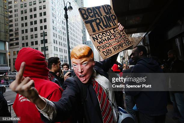 Man in a Donald Trump mask joins hundreds of other protesters and activists as they march during a demonstration near a midtown hotel which is...