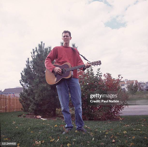 Portrait of American Country musician Robbie Fulks as he poses with his guitar outside his home, Chicago, Illinois, June 15, 2000.