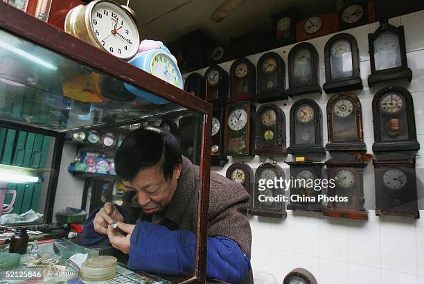 Worker repairs a clock at an antique clock store on February 2, 2005 in Chongqing, China. The old style of the store has attracted many tourists and...