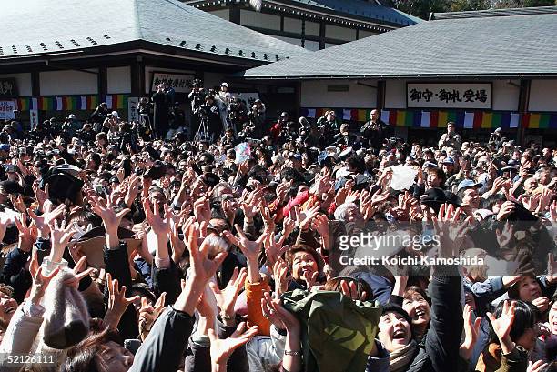 People reach out for the beans thrown by sumo wrestlers at the Shinshoji Temple to celebrate the coming of spring based on the lunar calender on...