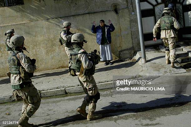 An Iraqi man puts his hands in the air as US soldiers from the 1st Battalion, 24th Infantry Regiment entry in his house during a joint patrol with...