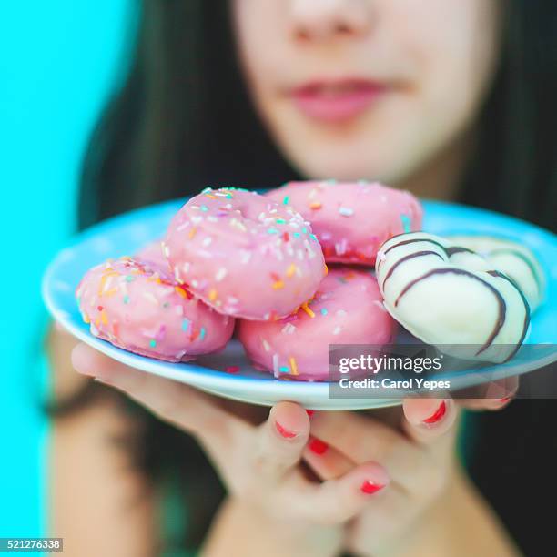 woman holding a plate with various pink donuts - fat people eating donuts foto e immagini stock