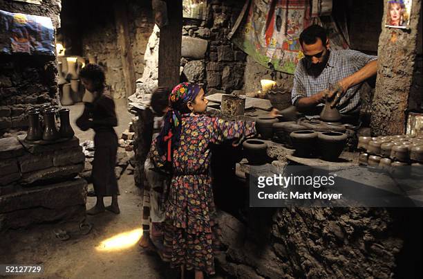 Children carry clay to a man working a pottery wheel in June, 1998 in Cairo, Egypt. The men, many who have been working at the factories since they...