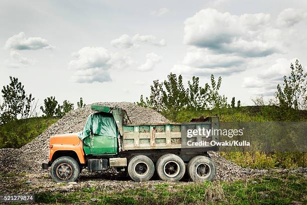 dump truck in front of gravel mound - camión de descarga fotografías e imágenes de stock