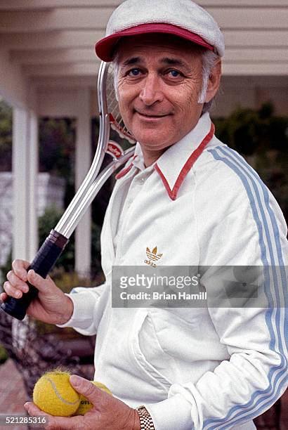 Portrait of American television producer Norman Lear as he poses with a tennis ball and racket at his home, Los Angeles, California, November 1974.