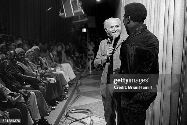 On the set of his tv 'The Jeffersons,' American television producer and writer Norman Lear shares a laugh with an unidentified man as he talks with...