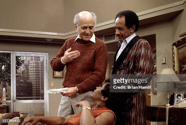 American television producer Norman Lear talks with actors Isabel Sanford and Sherman Hemsley on the set of their tv show 'The Jeffersons,' Los...