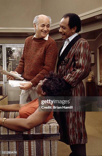 American television producer Norman Lear talks with actors Isabel Sanford and Sherman Hemsley on the set of their tv show 'The Jeffersons,' Los...