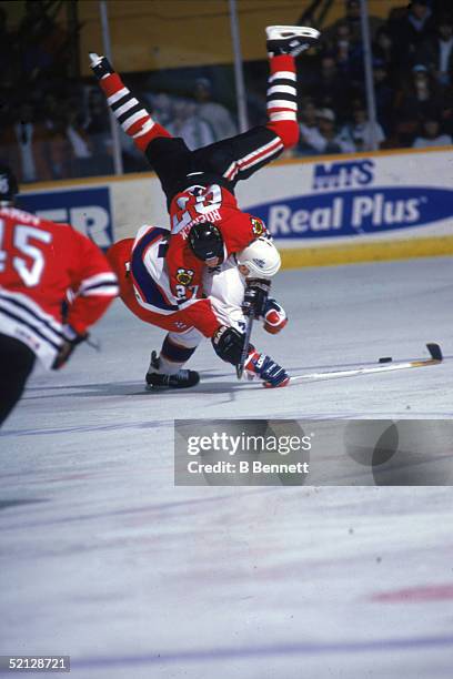 American professional hockey player Jeremy Roenick , center for the Chicago Blackhawks, stumbles over American professional hockey player Keith...