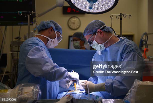 Dr. Mayur Jayarao, resident surgeon, left, and neurosurgeon Dr. Jonathan Slotkin, right, perform disc repair surgery on patient, Karen Hull at the...