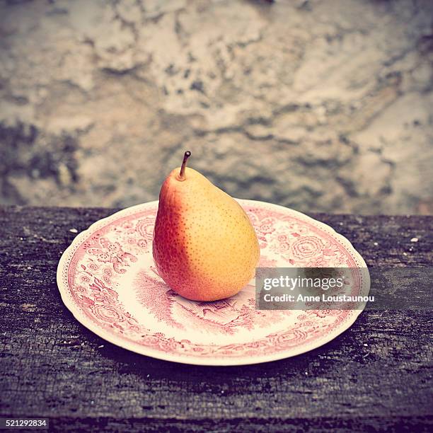 yellow and red forelle pear on antique plate on rustic farm table, france - forelle foto e immagini stock