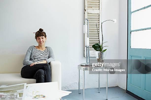 woman sitting on a sofa with prints - side table studio stock pictures, royalty-free photos & images